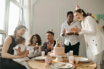 Un groupe d'amis diversifié célébrant un anniversaire à la maison avec un gâteau et des rires.