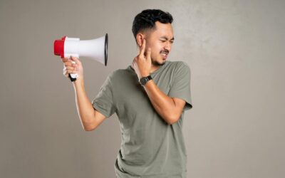 Un homme avec un mégaphone tenant son oreille en signe d'inconfort, représentant la pollution sonore ou des sons forts.