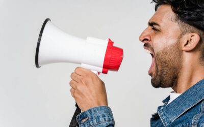 Gros plan latéral d'un homme criant passionnément dans un mégaphone, exprimant son urgence.