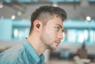 homme portant une chemise bleue avec des écouteurs Bluetooth noirs